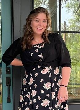 portrait of delany post wearing a black dress with pink flowers on it.