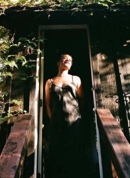 portrait of Chi Adi standing in a doorway surrounding by foliage